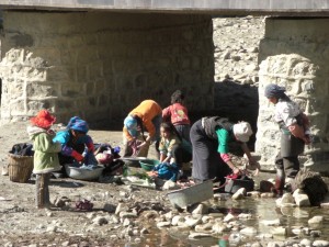 am Weg zum Kloster tibetisches Leben - Waeschewaschen im Fluss, der durch den Ort fliesst