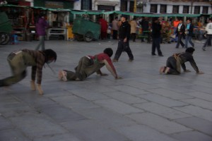...weitgereiste Pilger prostrieren mit tibetischen Praxissinn - bewehrt mit Holzplatten auf Haenden und Knien lassen sie sich mit viel Schwung zu Boden fallen um moeglichst viel Strecke rutschend zurueckzulegen :-)